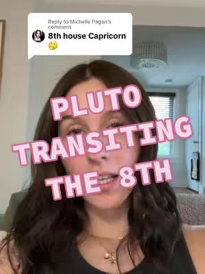 A young woman with long brown hair looks directly at the camera. She has a light complexion. A light pink text overlay reads, “Pluto Transiting the 8th” in a bubble-letter font. The background is a soft focus of a room with neutral colors.