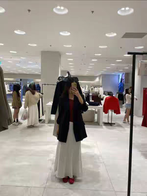 The cover image shows a woman taking a selfie in a brightly lit clothing store. She is reflected in a mirror while holding her phone up for the shot. The layout showcases the store's interior, with racks of clothing and other shoppers in the background.