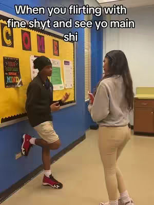 A scene from a school setting, with two students. A male student is leaning against a wall, looking at a female student. They are in a hallway with a bulletin board and a door.