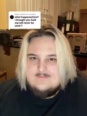 A man with blonde hair, a beard and a black shirt is the focus. Above his shoulder is a white text bubble with black text in a kitchen setting.