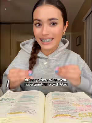 A young woman with a braid and braces is seated in front of an open Bible, with overlaid text. She is smiling, and her hands are near the pages.