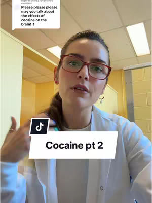 A woman with red-framed glasses and a white lab coat is looking directly at the camera. A comment overlay requesting discussion about "the effects of cocaine on the brain" and a title overlay on the bottom that says "Cocaine pt 2". The background suggests an office setting.