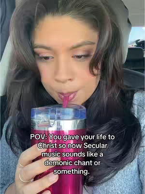 A woman is shown in a selfie-style shot, looking down as she sips from a large pink tumbler. The backdrop is out of focus, but suggests the inside of a vehicle. The photo's lighting is soft, with the focus on the woman's face and the drink she is holding.