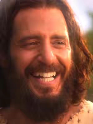 The cover image is a close-up shot of a man with long brown hair and a beard. He has a warm smile, showing his teeth, and appears to be laughing. The lighting suggests a sunny outdoor setting.