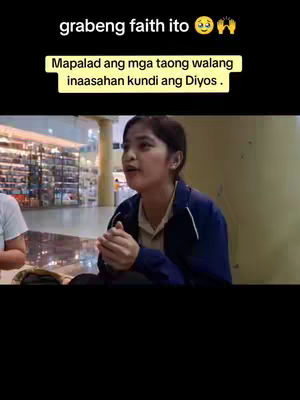 The image shows a woman in a blue jacket sitting in a public space, possibly a mall. She has her hands clasped together in a praying gesture. A yellow rectangular text overlay contains a quote in Filipino. In the background, there are blurred shop displays.