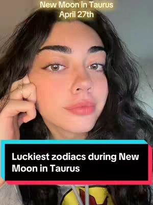 The cover image shows a woman with long dark hair. The background behind her is out of focus, and she has a light complexion. On the top of the image, there is text that reads, "New Moon in Taurus April 27th". The image features a text overlay that reads "Luckiest zodiacs during New Moon in Taurus”.