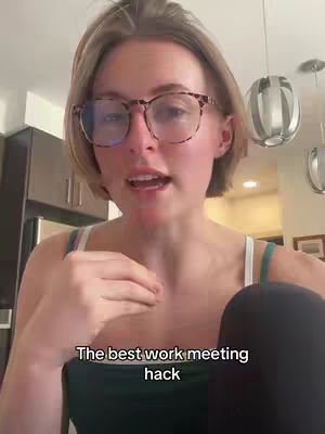 A woman with short blonde hair and glasses is speaking. The background is a kitchen with a dark refrigerator.