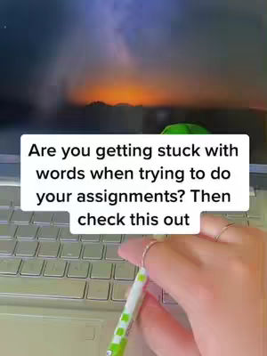 The image captures a hand interacting with a laptop keyboard, focusing on the hand over the keys and a text overlay. The background shows a blurry sunset or evening sky through the laptop screen. The composition is simple, with a close-up perspective.