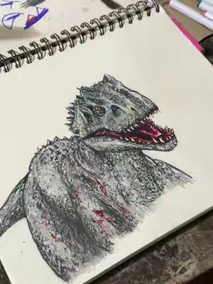 A close-up drawing of an Indominus Rex from Jurassic World, done in a sketchbook. The dinosaur is rendered in gray and black with red blood-like markings over its body and open mouth displaying sharp teeth. The image is positioned with the spiral binding of the sketchbook visible along the left edge.