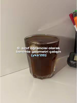 The image shows a glass filled with a dark liquid, possibly coffee or tea, set on a white surface. Text is overlaid on the image.