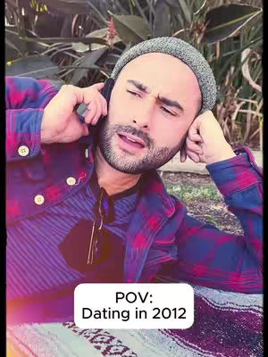 A man is seen outdoors, leaning against a background of foliage, holding a phone to his ear. He has a beanie and a plaid shirt. Text on the image reads "POV: Dating in 2012".
