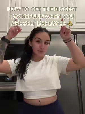 A woman stands in a kitchen with white cabinets in the background, pointing her fingers up. Text overlays the image, providing context. The woman wears a white t-shirt and dark-colored pants. Her hair is black and long, pulled back with some parts hanging loose. She has tattoos on her arm. A watch is on her wrist.