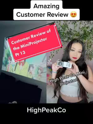 A split-screen image with a young woman on the right holding a mini projector, smiling at the camera. On the left a projected image of an animation displayed on a wall. Rectangular text boxes overlay the screen with text to promote the product and highlight a customer review.