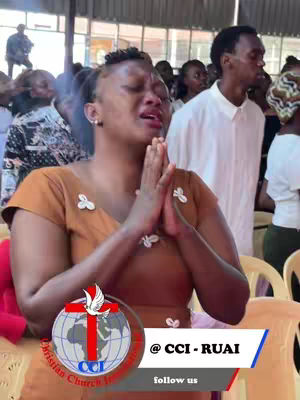 A woman in a brown dress is in a crowd, her hands pressed together in prayer. A logo of a globe with a cross is visible, along with text. The background shows a blurry gathering, suggesting a church setting.