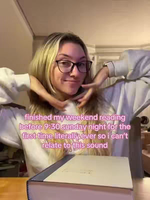 A young woman with long blonde hair, wearing glasses and a white sweater, smiles at the camera. Her hands are raised, framing her face, with a book visible in front of her on a wooden table. Text overlays the image.