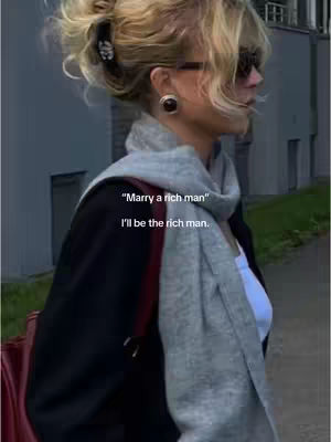A woman in sunglasses, a gray scarf, and a black blazer stands outside. Text overlays state, " 'Marry a rich man'  I'll be the rich man."