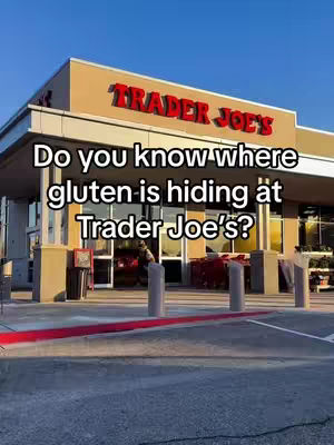 The cover image shows the exterior of a Trader Joe's store on a sunny day. The iconic Trader Joe's logo is prominently displayed in red on a beige background. The text overlay on the image asks, "Do you know where gluten is hiding at Trader Joe's?" The overall composition is clean and bright, focusing on the store's entrance with a clear sky in the background.