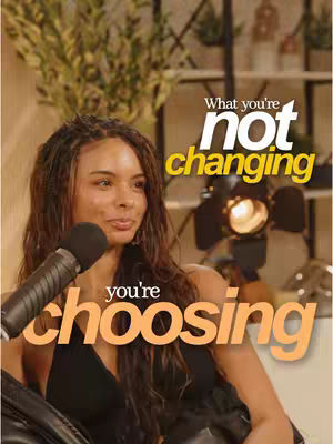 A woman with long brown hair sits in front of a microphone. Text overlays read, "What you're not changing" in an orange and white font, and "you're choosing" in a similar font below. The background is a blurred room setting.