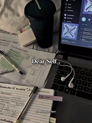 The image shows a workspace setup. A laptop is open, displaying a screen, with earphones draped over the keyboard. Scattered around are papers with handwritten notes, a notepad with a pink sticky note, a pen, and a black tumbler. The layout is seen from a bird's-eye view, with the focus on study materials.