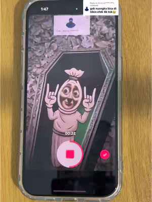 The cover image shows a phone screen displaying what looks like a TikTok video in progress. The phone is held vertically against a wooden surface. Inside the video, a cartoonish character resembling a white sack with drawn-on features and devil horns is shown rising out of a coffin. There are text overlays and TikTok user interface elements visible, including a timer.