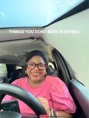 A woman with glasses and a pink shirt is seated in the driver's seat of a car, looking at the camera and smiling. The text overlayed on the cover, "THINGS YOU DONT NEED IN SPRING," appears at the top of the frame. Part of the steering wheel is visible in the foreground.