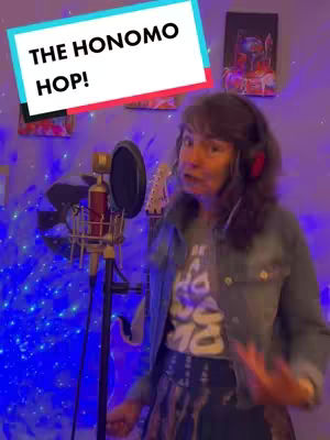 A woman with headphones and a denim jacket is in a room lit with blue lights, holding a microphone. A text overlay reads 'THE HONOMO HOP!'