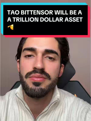 A man with dark hair and a beard is centered in the frame, wearing a light-colored sweater. Above him, a banner displays white text on a black and red background. The image has a well-lit, direct quality.