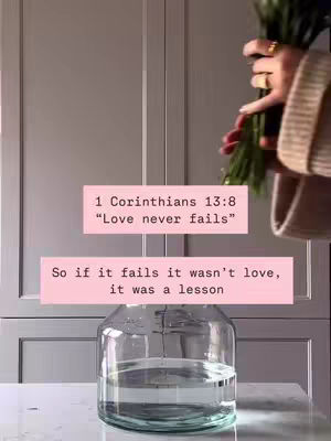 The image shows a close-up shot of a glass vase with water on a marble surface. Two pink rectangular text boxes with white text overlay the image. A hand holding some green stems is partially visible from the right of the frame offering an appealing contrast with the muted background made of closet doors.