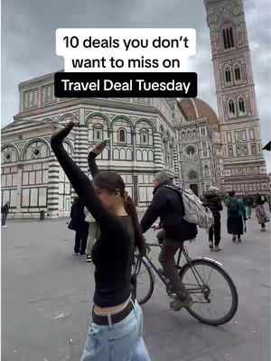 A woman stands in front of a large building, possibly a cathedral, with her arms raised. A person on a bicycle passes by. Text overlays at the top and bottom of the image.