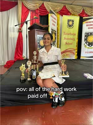 The cover image shows a young woman seated with numerous trophies and awards in front of a stage setting. She is smiling while holding a trophy, wearing a white dress. The background includes banners and stage curtains.