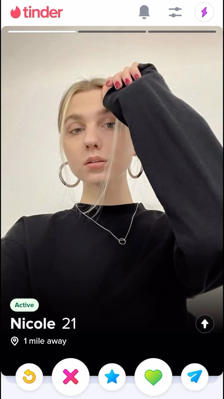 The cover image shows a screenshot of a Tinder profile. The profile picture features a young woman with blonde hair, wearing a black sweater, and silver hoop earrings holding up her hand. The Tinder interface includes the app's logo, a bell icon, and a settings icon at the top, with profile details at the bottom.