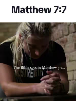 A woman with long blonde hair is shown from the chest up, her hands clasped in prayer. The top part of the image features the text "Matthew 7:7". The background is a blurry mix of brick and shadow. The woman wears a dark shirt and seems to be in a moment of reflection or prayer.