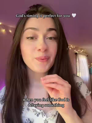 A woman with long brown hair, fair skin, and a soft expression, looking directly at the camera. She is wearing a light-colored top with a detailed floral pattern. Above her head, the text "God's timing is perfect for you."