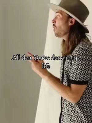 A man in a hat and a patterned shirt looks upwards and to the side, with text overlayed on the image.