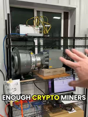 A person's hand gestures towards a crypto mining setup on a black metal shelf.  Various components of the crypto mining operation fill the shelf. A sign states "Fan is Going Down" in a hand-scrawled font. The video also shows a computer screen indicating the mining data with the text "ENOUGH CRYPTO MINERS" in the bottom mid-section of the screen.