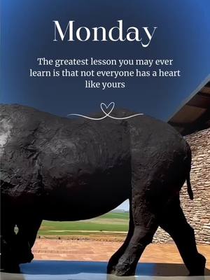 The image features a striking black sculpture of a large animal, possibly a buffalo or a bull, set against a backdrop of a landscape and a deep blue sky. Above the sculpture, the word "Monday" is written in a clean, white font. Below it is a quote that encourages empathy and understanding of others. The composition is balanced with a mix of natural and architectural elements.