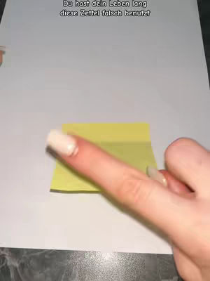 The video shows a close-up view of a hand holding a yellow sticky note. The finger points towards it. At the top is text in German.