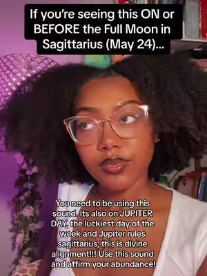 A woman with dark curly hair and glasses is centered in the frame. Text overlays are at the top and bottom. She is looking directly at the camera and making a slight smile. 