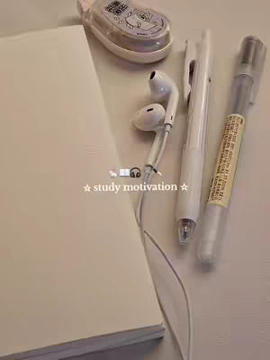 A top-down shot of study supplies arranged on a cream-colored surface. A mostly closed notebook and headphones are positioned at the left. To the right are a white pen, a clear highlighter with a yellow label, and a white correction tape dispenser. The image's primary colors are muted whites and beige, creating a minimalistic and organized feel. Overlayed text in a star-framed font reads 'study motivation'.