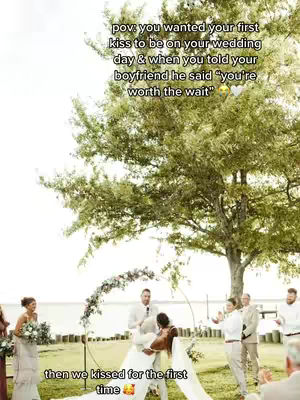 A wedding photo with a couple kissing under an arch. Text overlays describe the moment. The scene is set outdoors with a large tree in the background, providing a natural setting.