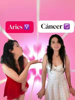 Two women are featured in the image. On the left, a woman in a red dress blows a kiss towards the center, with her arm extended. On the right, another woman in a white dress is positioned, facing forward, with her arms down. Above these figures, two banners are displayed: one reads "Aries" on a pink background, while "Cáncer" is noted on a white background. The backdrop is a gradient of pink hues with heart-shaped patterns, enhancing the romantic theme.