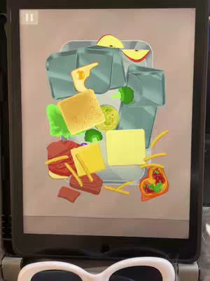 An iPad displays a colorful illustration of various food items, including squares, slices, and other shapes. The foreground includes a pair of white sunglasses.