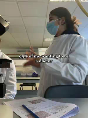 The cover image is an interior shot, likely a lab. A woman, with her face partially visible, is wearing a blue surgical mask and a white lab coat. Text overlayed on the image says, '99% of me wanting to be a doctor'. The background includes lab equipment and countertops, suggesting a medical or scientific environment.