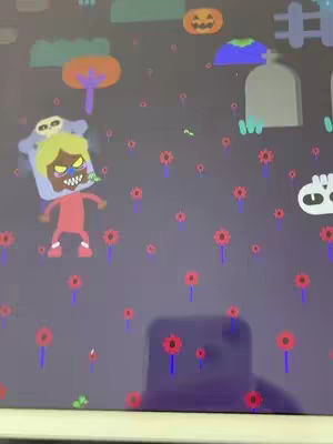 An illustration depicting a Halloween scene. The background is a dark purple with cartoonish elements scattered around. A central figure, possibly a character dressed in a red jumpsuit and a skull mask with yellow hair, is positioned towards the left. There are several scattered red flowers with blue stems. Halloween related elements like a jack-o'-lantern, a tombstone, and a skull are present in the image.