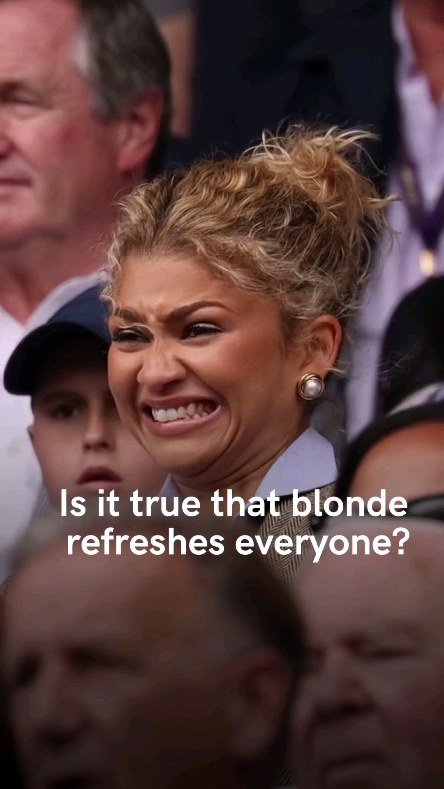 The image appears to be a close-up of Zendaya looking at something off-camera with a disgusted expression. Her blonde hair is styled in a messy updo, and she wears pearl earrings. The background is blurred, but it seems to be an outdoor setting.  Text overlayed on the image asks a question related to the color blonde.