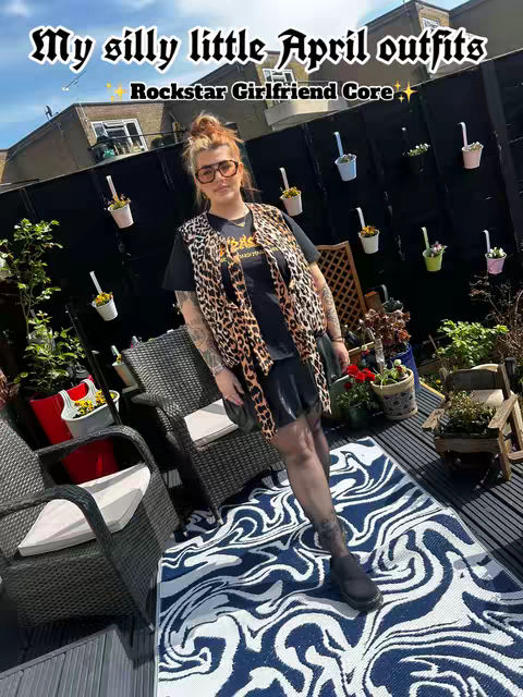 The cover image showcases a person outdoors in a garden setting. The individual is wearing a black t-shirt layered under a leopard-print vest. They are also wearing black sheer tights and shoes. The background includes a blue sky, green trees, and black fences decorated with potted flowers, accompanied by wooden chairs and a deck with a blue and white patterned rug. Text overlays are placed at the top of the image.