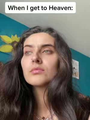The image shows a close-up of a woman's face, set against a background of teal-colored wall with a yellow floral design. The woman has long, dark hair and is looking slightly upwards. Text overlay at the top reads 'When I get to Heaven:'.