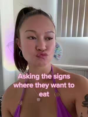 A woman with pulled-back dark hair pouts with her lips pursed. She wears a purple top and a necklace with a white pendant. Text is overlayed in light pink.