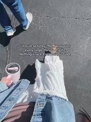 The image is a top-down shot, showing the lower body of a person wearing blue jeans, a white top, and a light-wash denim jacket. The person is holding a pink tumbler. In the background, a person in blue jeans is walking on a gray surface. Text overlay is at the center, and the composition is straightforward.