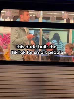 A video captured on a subway or train, seen through the window. A man is standing and talking to someone off-camera, holding a phone. The focus is on the sign placed text over the scene.